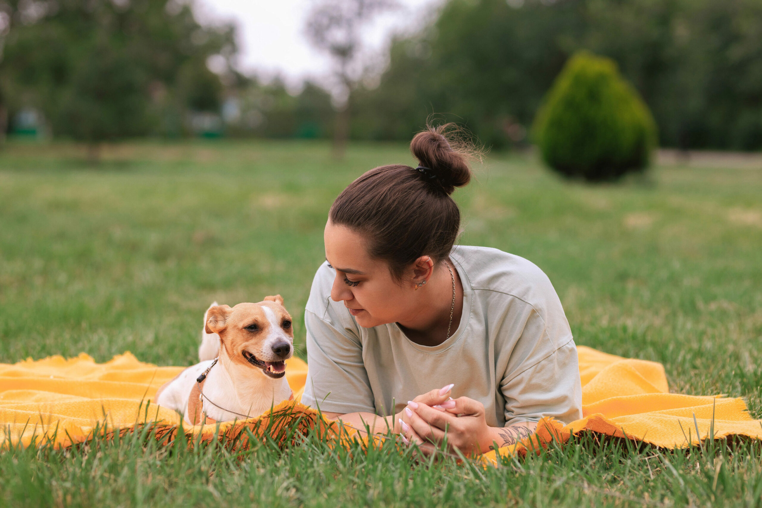 Dog owner laying in field with her Jack Russell Terrier